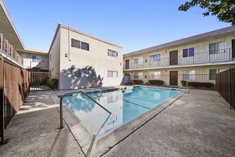 A swimming pool in front of a building with a blue sky in the background.
