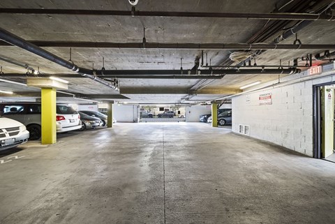 A parking garage with a concrete floor and yellow poles.