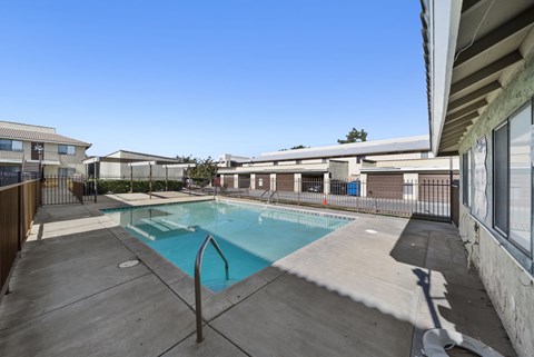 A swimming pool surrounded by a concrete deck and a metal fence.