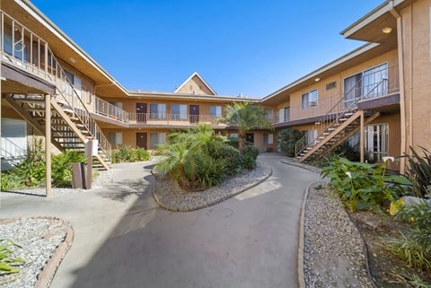 A courtyard with a pathway and plants in front of apartment buildings.