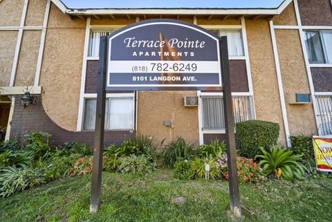 A sign for Terrace Pointe Apartments stands in front of a building.