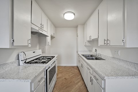A kitchen with white cabinets and granite countertops.