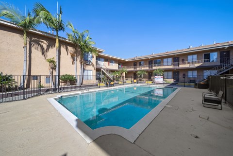 A swimming pool surrounded by palm trees and a building.