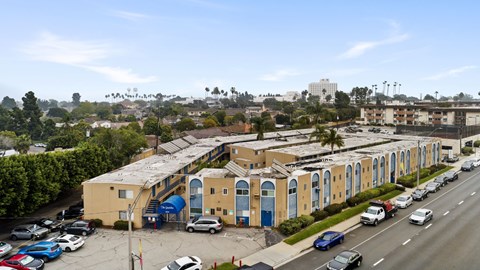 A parking lot with cars and a yellow building with blue doors.