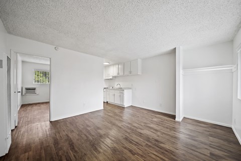 A large empty room with wooden floors and white walls.