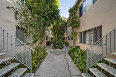 A pathway leads through a courtyard with a metal fence on either side.