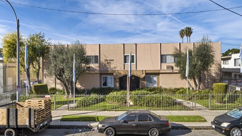 A beige building with a black car parked in front of it.