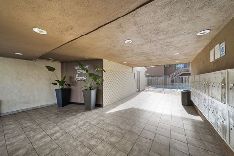 A hallway with a sign that says "Well we town" and a plant in a pot.
