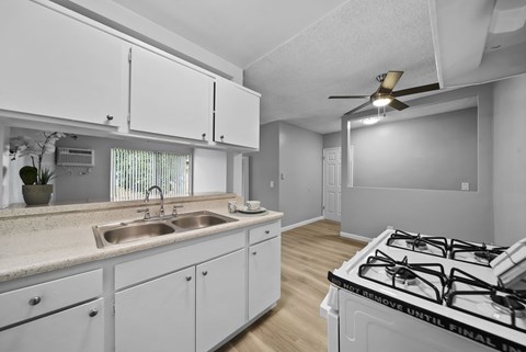 A kitchen with white cabinets and a stove top oven.