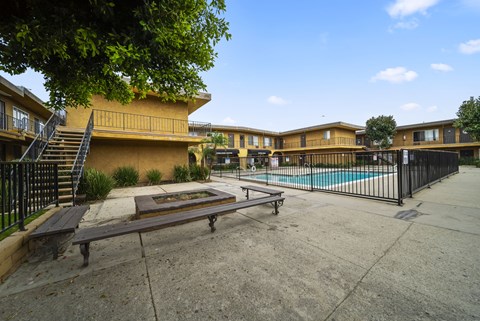 A pool and patio area of a building with benches.