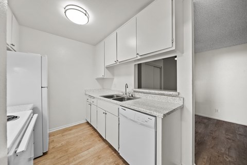 A small, white kitchen with a sink and a refrigerator.