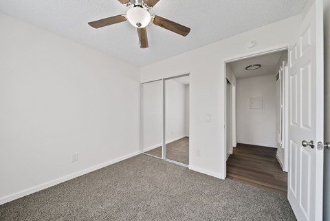 A room with a ceiling fan and sliding doors.