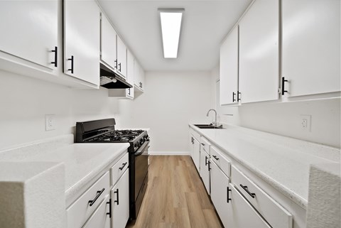 A kitchen with white cabinets and a black stove top oven.