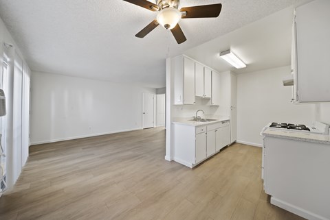 A kitchen with white cabinets and a wooden floor.