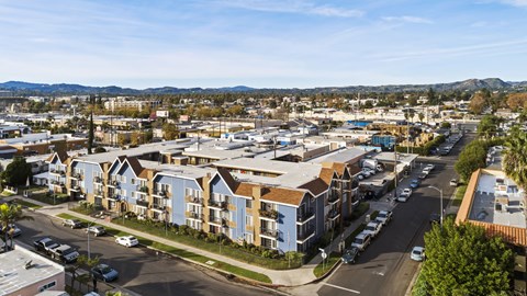 A view of a residential area with apartment buildings and cars parked on the street.