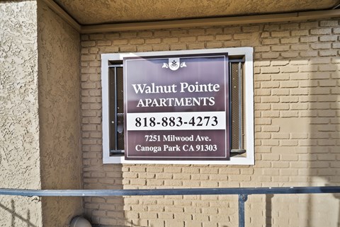 A sign for Walnut Pointe Apartments is on a building.