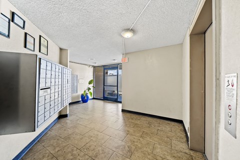 A hallway with a blue vase and a fridge on the left.