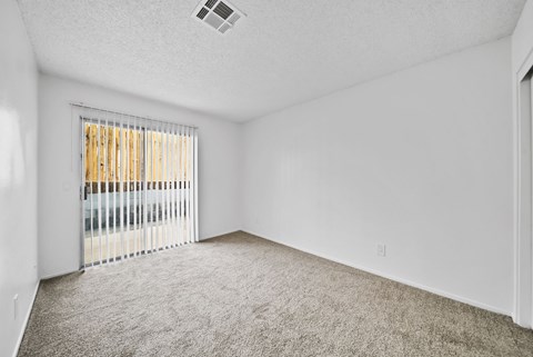 A room with a carpeted floor and a window with blinds.