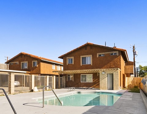 A house with a brown exterior and a pool in front.