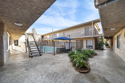 A concrete courtyard with a pool and a metal fence.
