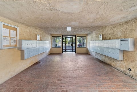 A long hallway with a brick floor and white lockers on the wall.