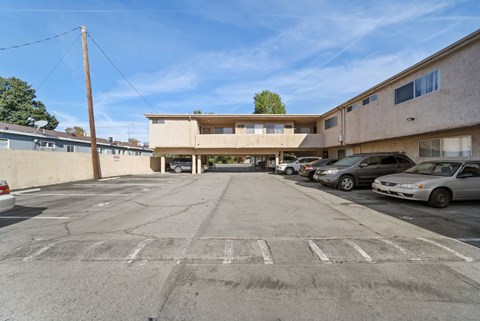A parking lot with a building in the background and several cars parked.