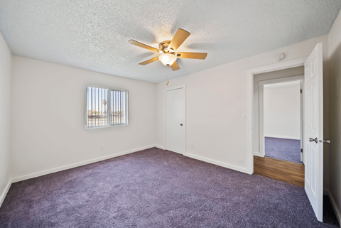 A room with a ceiling fan and a window with blinds.