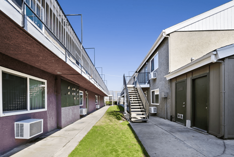 A long, narrow courtyard between two buildings with a staircase in the middle.