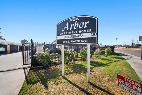 A sign for Arbor Apartment Homes is displayed in front of a gated entrance.