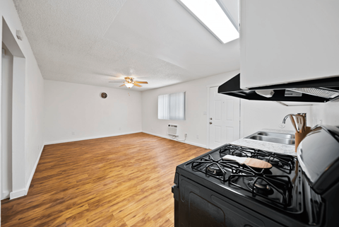 A kitchen with a black stove top oven and wooden flooring.