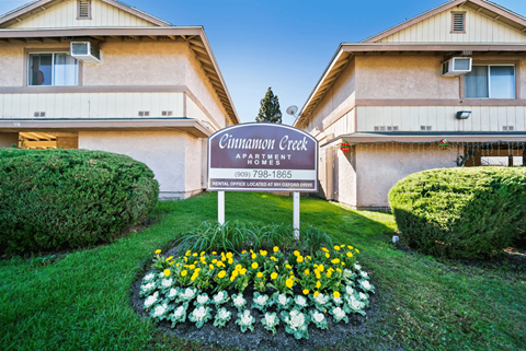 A sign for Cinnamon Creek Apartment reads "Apartments for Rent" and includes a phone number.