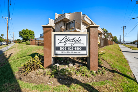 A sign for Lifestyle Apartments with a phone number and address.