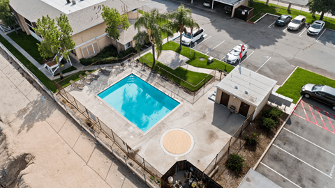 An aerial view of a pool surrounded by a fence and a parking lot.