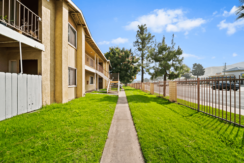 A long concrete walkway leads between two rows of apartment buildings.