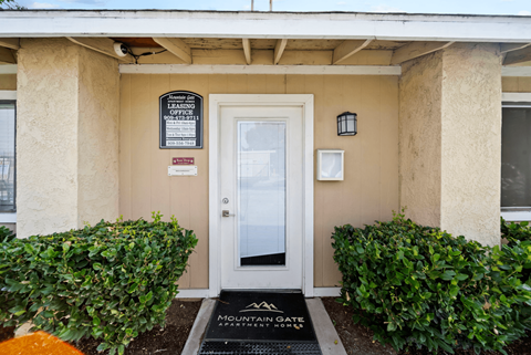 The front door of a building with a sign that says "Mountain Gate Apartments".