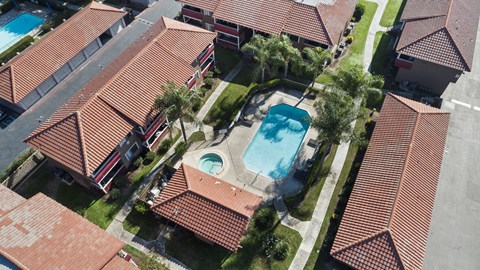 A swimming pool is surrounded by a red tiled roof.