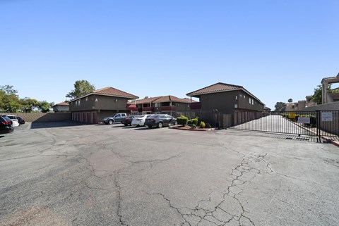 A parking lot with several cars and buildings in the background.