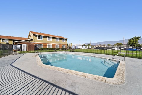 A small pool in a concrete area with a building in the background.