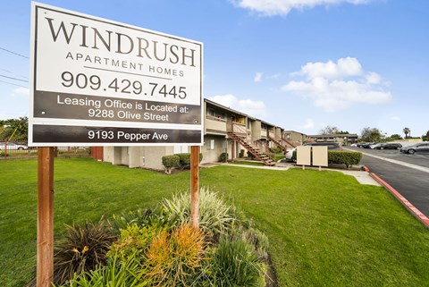 A sign for Windrush Apartment Homes is in front of a building.