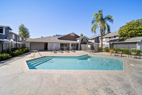 A swimming pool in a residential area with houses and palm trees.