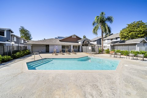 A swimming pool in a residential area with houses and palm trees.