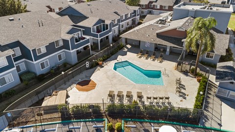 A pool surrounded by chairs and a fence in front of a building.