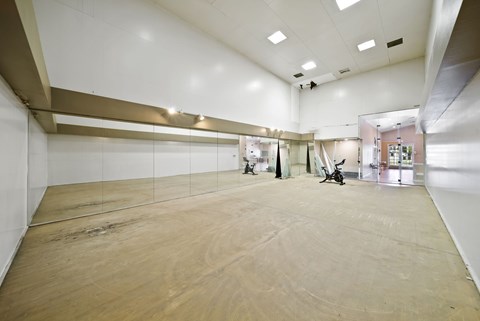 A large empty room with wooden flooring and white walls.