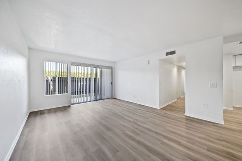 A spacious room with a sliding door and hardwood flooring.