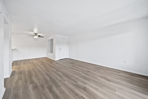 A room with a ceiling fan and a wooden floor.