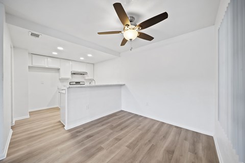 A room with a ceiling fan and wooden flooring.