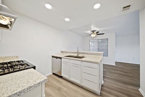 A kitchen with a black gas stove and white cabinets.