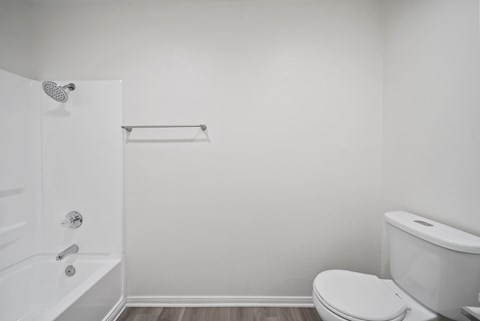 A white bathroom with a toilet, tub, and shower.