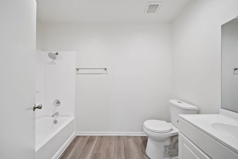 A white bathroom with a toilet, sink, and bathtub.