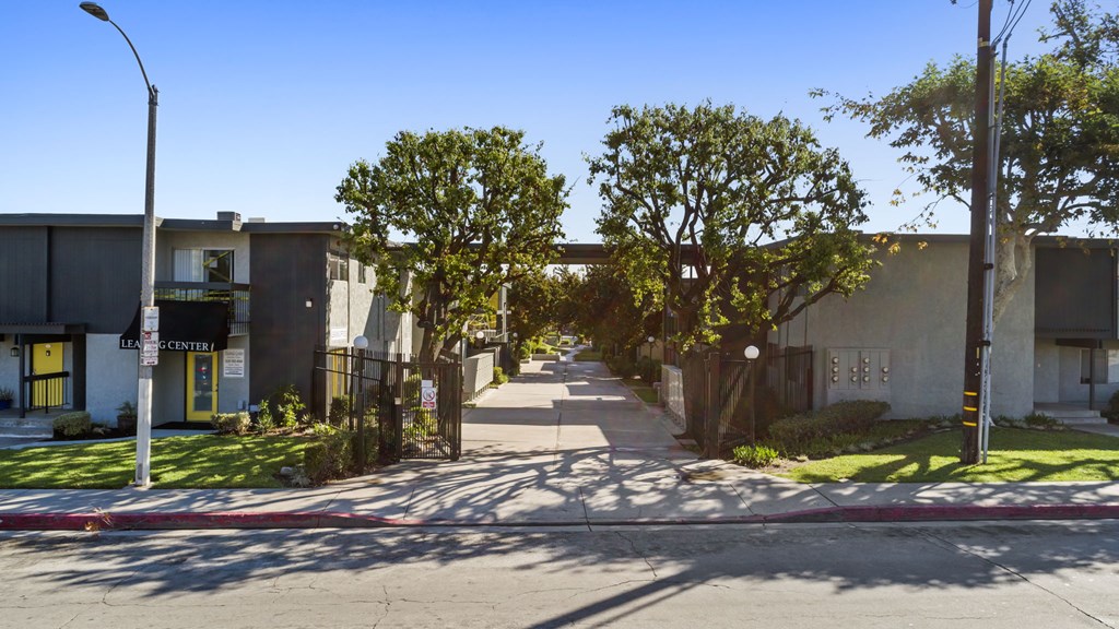 A street view of a residential area with houses on both sides and a clear blue sky.